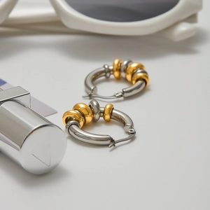Detail of minimalist mixed metal earrings in 18K gold and stainless steel finishes