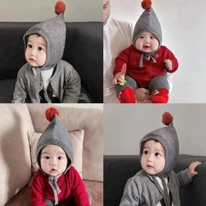 Dettaglio del cappello in maglia grigia per neonati con pompon arancione e paraorecchie