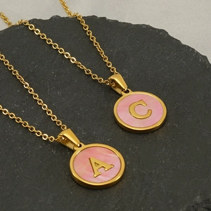 Détail des pendentifs lettres A et C dorés avec incrustation rose sur la chaîne