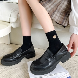 Women's black platform loafers paired with cute bear embroidery socks in a cozy room