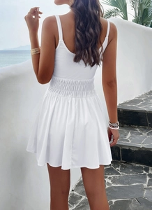 Back view of a white sleeveless A-line dress with elastic waist in a coastal setting