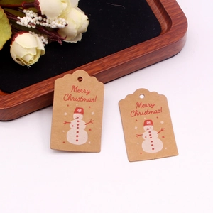 Macro shot of kraft paper Christmas tags featuring a red snowman and Merry Christmas greeting