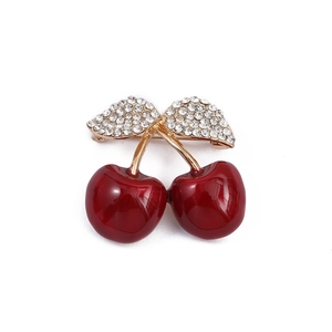 Detailed close-up of red cherry brooch with gold leaves and inlaid crystals
