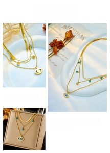 Detailed view of triple-layered gold chain necklace with turquoise beads and evil eye pendant