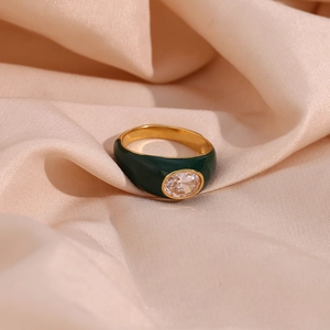 Macro shot of gold-plated ring with dark green enamel and oval cubic zirconia on silk