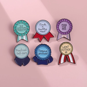 Set of 6 colorful medal-shaped enamel pins with motivational quotes on pink background