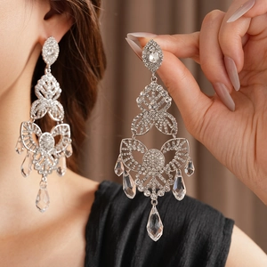 Detail of silver drop earrings with floral rhinestones and long tassels on earlobe