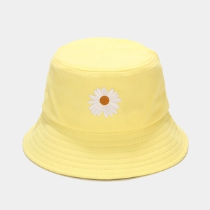 Close-up of small daisy flower embroidery on a bright yellow cotton bucket hat