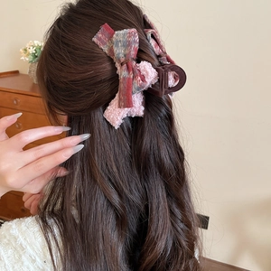 Detail view of large red and blue plaid velvet bow hair claw clip worn by model