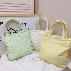 Detailed view of macaron colored quilted handbags featuring minimalist floral patterns