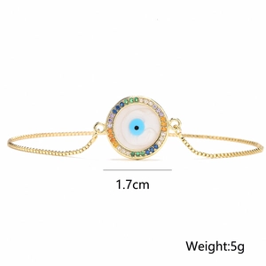 Macro detail of 18K gold Evil Eye bracelet with colorful crystals and enamel pendant