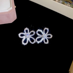 Detailed close-up of sparkling flower-shaped stud earrings with full diamond inlay on black velvet