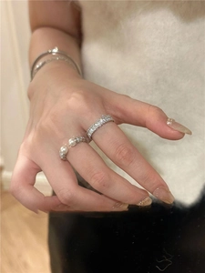 Macro shot of silver stackable pearl and zircon rings set on female fingers