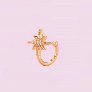 Detail of a gold ear bone clip featuring a sparkling sunburst zircon star design