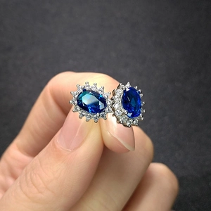 Macro shot of sapphire blue oval earrings with sparkling white diamond halo detail