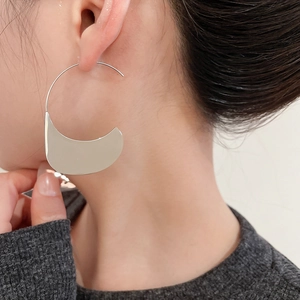 Macro side view of large silver crescent hoop earrings on model with high gloss finish