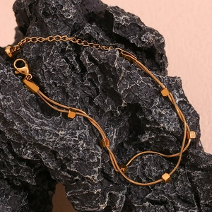 Detailed close-up of 18K gold plated double layer snake chain bracelet on black stone