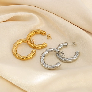 Detailed macro view of gold and silver twisted hoop earrings on soft silk fabric