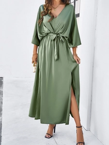 Detail of elegant green satin dress featuring a V-neckline and tie waist design