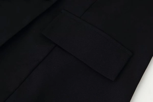 Detailed view of the black jacket pocket flap with premium woven fabric and precision stitching