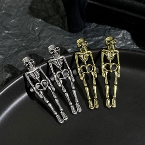 Macro view of gold and silver gothic skull earrings on a black ceramic tray