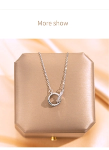Close-up of interlocking silver double ring necklace with zircon inlay on jewelry box
