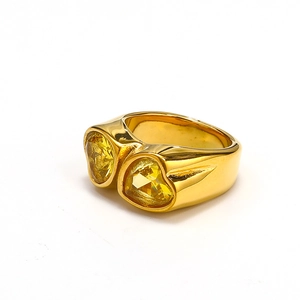 Detail view of gold wide band ring featuring two sparkling yellow heart shaped gemstones