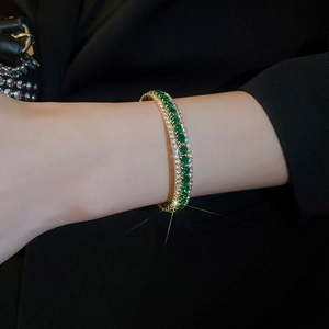 Close-up of a three-row emerald and diamond paved gold cuff bracelet on wrist