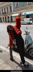 Outdoor street style shot of vibrant red fur jacket paired with black wide-leg pants