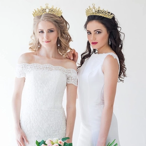 Close-up of two bridal crystal crowns featuring gold plating and shimmering rhinestones