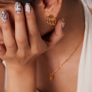 Close-up of triple-layered 18K gold-plated geometric hoop earrings on a female model