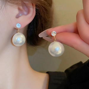 Vue détaillée d'une grande perle blanche et d'un clou en zircon portés à l'oreille