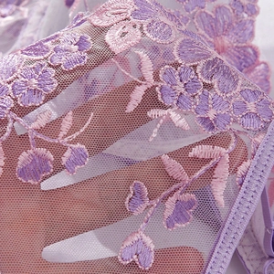 Macro shot of purple floral lace embroidery on semi-transparent mesh fabric detail