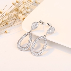 Elegant silver S925 drop earrings with pave-set crystals on a white ceramic display