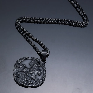 Detail of St. George dragon relief on round black metal pendant with woven chain