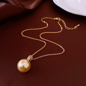 Gros plan sur le pendentif perle champagne et la chaîne en or 18 carats