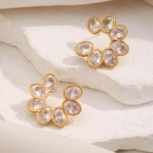 Detail of gold-plated 18K flower stud earrings with clear zircon on stone background
