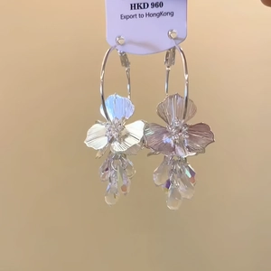 Detail of silver floral earrings with crystal droplets and intricate textured flower petals