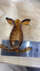 Close-up of 5cm amber resin hair claw clip showing precise size measurement on wood surface