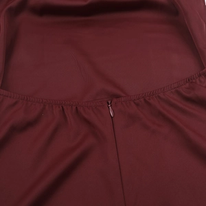 Detailed close-up of hidden zipper and stitching on a burgundy satin evening dress