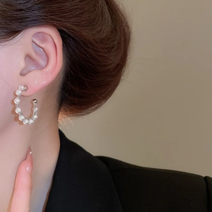 Close-up of minimalist C-shaped hoop earrings featuring lustrous white pearls for women
