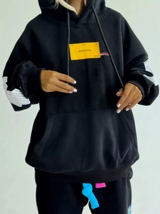 Oversized black hoodie with yellow graphic patch and white sleeve prints for street style