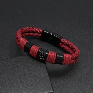Detail of red braided leather bracelet featuring a black magnetic clasp on textured background
