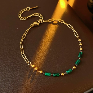 Détail du bracelet chaîne dorée vintage avec pierres de malachite verte sur cuir sombre