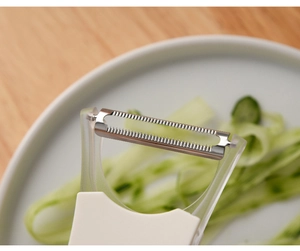Close-up of serrated dual-blade vegetable peeler creating fine cucumber shreds