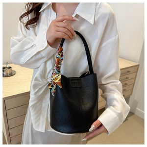 Detail of black lychee grain leather bucket bag with a colorful decorative silk scarf