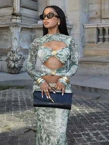 Detail of waist cutouts and gold floral metal buckle on a green tie-dye maxi dress