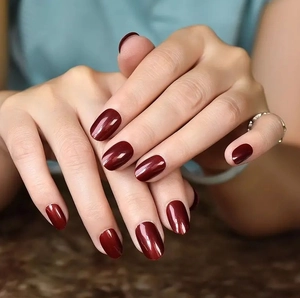 Uñas postizas ovaladas rojo intenso brillante con efecto espejo en manos cruzadas
