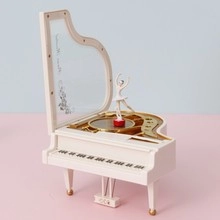 Close-up of white piano music box featuring a spinning ballerina on a soft pink background
