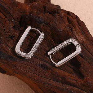 Close-up of silver rectangular hoop earrings with pavé stones on a wooden background